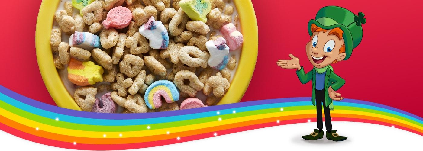 Lucky el duende señala un bol de cereales de Lucky Charms Marshmallow Clusters puestos encima de un arcoíris.