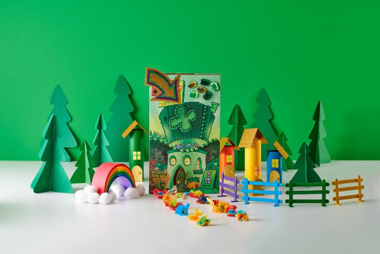 A colorful homemade leprechaun trap sitting on table surrounded by paper trees