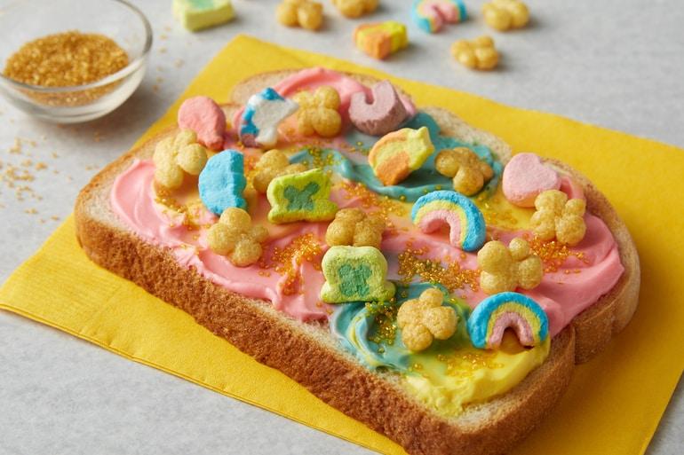 Leprechaun Rainbow Toast with rainbow spread topped with Lucky Charms™ Honey Clovers cereal.